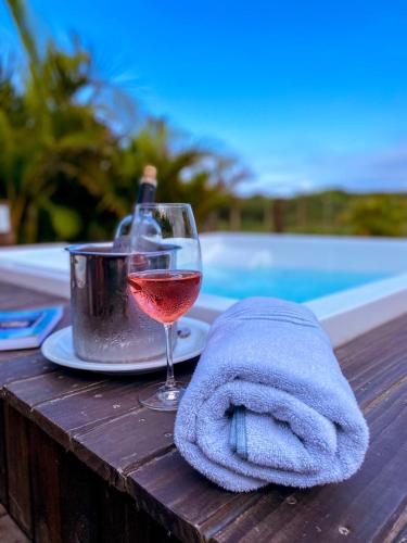 a glass of wine sitting on a table by a pool at Pousada Ilha Faceira in Florianópolis