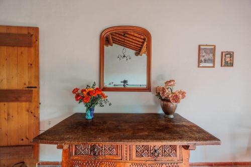 a table with a mirror and two vases with flowers on it at Apartment with view and garden - Quercia in Ghizzano
