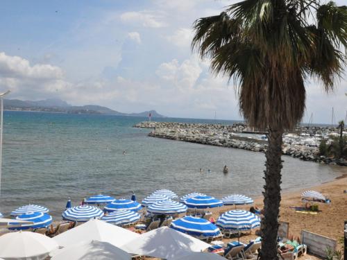 a beach with blue and white umbrellas and a palm tree at Villa in Fayence with Provençal Charm in Fayence