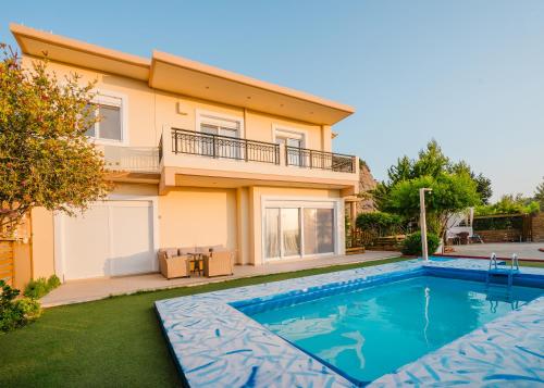 a villa with a swimming pool in front of a house at Dreamcatcher Villa in Pastida