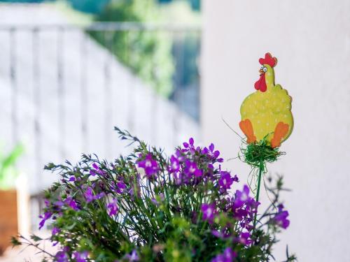 a chicken ornament sitting on top of purple flowers at Apartment in La Omañuela in La Omañuela