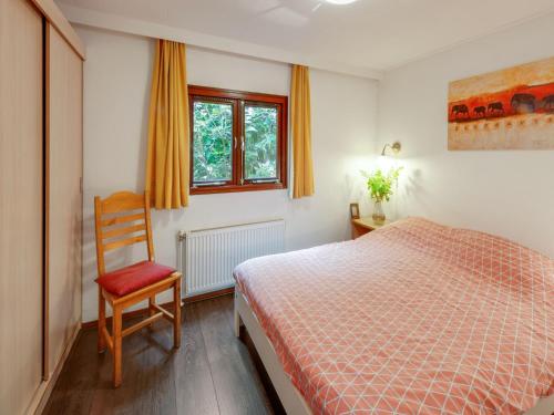 a bedroom with a bed and a chair and a window at Chalet in Stegeren with Pool and Gardens in Stegeren