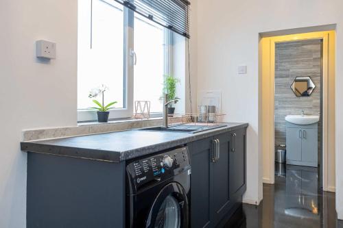 a kitchen with a sink and a washing machine at Modern & Convenient 2 Bedroom House in St Helens in Saint Helens