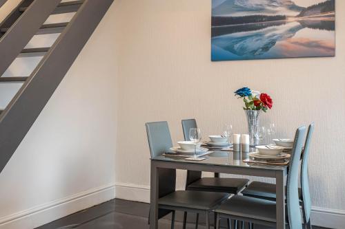 a dining room table with chairs and a vase with flowers at Modern & Convenient 2 Bedroom House in St Helens in Saint Helens