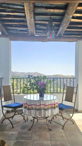 a table and chairs with a vase of flowers on it at Casa Rural La Chaparra - Apartamento Atalbéitar in Pitres