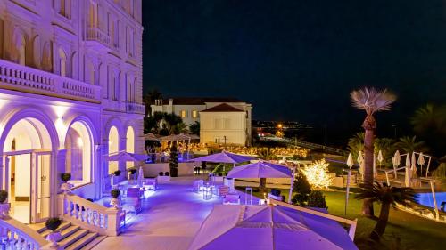 an outdoor patio with purple umbrellas at night at Miramare The Palace Resort in Sanremo