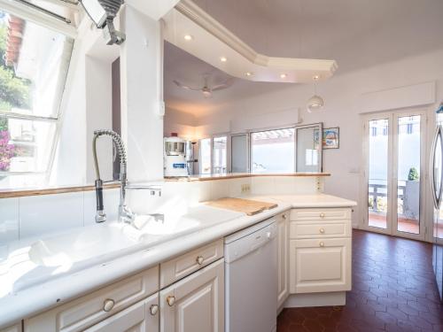 a kitchen with white counters and a sink and windows at Elegant Seaside Villa in Èze in Èze