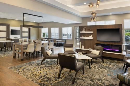 Residence Inn Tampa Suncoast Parkway at NorthPointe Village في لوتز: غرفة طعام مع طاولة وكراسي وتلفزيون