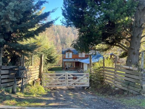a house with a wooden gate and a fence at Casa en medio de la montaña in San Martín de los Andes