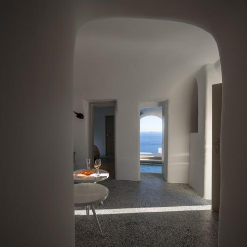 a hallway with a table and a view of the ocean at Echoes Luxury Suites in Oia