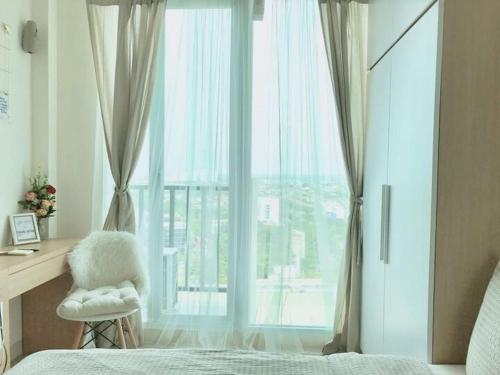 a bedroom with a bed and a desk and a window at Apartemen Treepark BSD By LyaRoom in Dadap