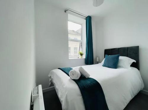 a bedroom with a large white bed with blue accents at Spacious 2-Bed Apartment in Watford