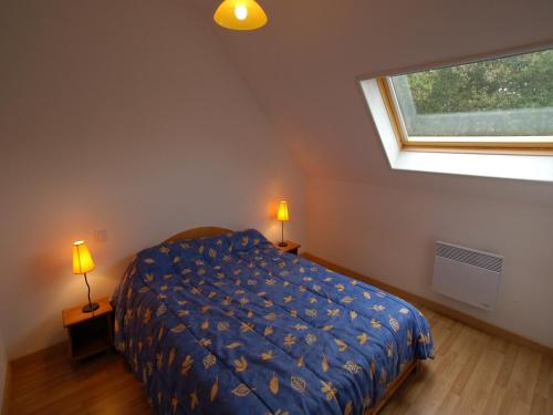 a bedroom with a bed with a blue comforter and a window at Coastal Retreat in Plurien in Plurien