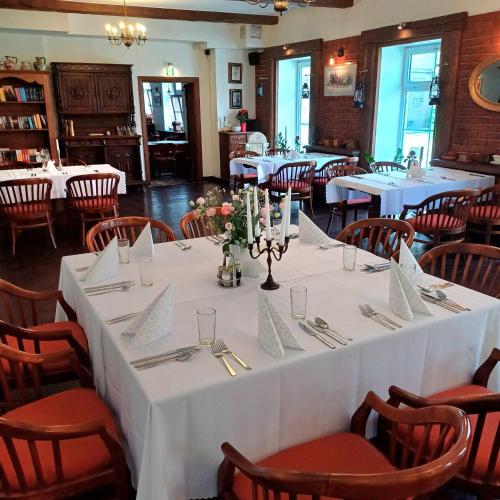 a table in a restaurant with white tables and chairs at Hotel Zajazd Kultury, dawniej Pocztowy in Zielona Góra