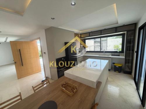 a living room with a white table and a kitchen at Maison haut standing a côté de la palage in Bizerte