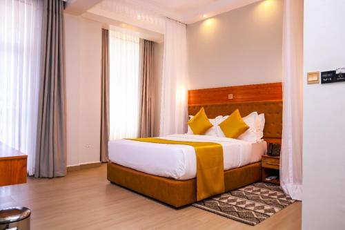 Cette chambre comprend un grand lit avec des oreillers jaunes. dans l'établissement Lake Naivasha Parklane Resort, à Munyu