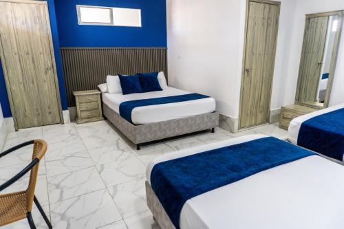 a bedroom with two beds and a blue wall at Hotel Bello Caribe Rodadero in Santa Marta