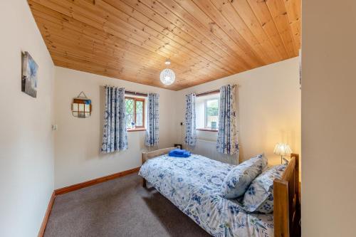 a bedroom with a bed and a wooden ceiling at Stabyl-Y-Ddol in Glyn-Ceiriog