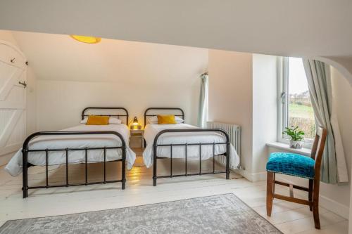 two beds in a room with a table and a chair at Hywelfa in Abersoch