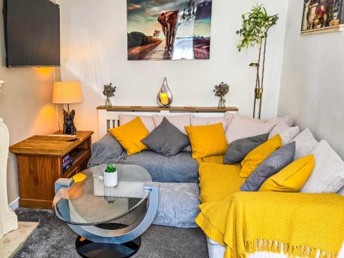 a living room with a couch with yellow pillows at Tree Tops by StayStaycations in Glyncorrwg