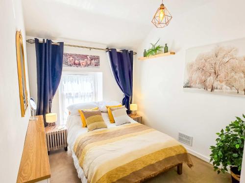 a bedroom with a bed with blue curtains at Tree Tops by StayStaycations in Glyncorrwg