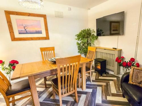 a dining room with a table and chairs and a fireplace at Tree Tops by StayStaycations in Glyncorrwg