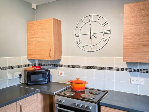 a clock on the wall above a stove in a kitchen at Tree Tops by StayStaycations in Glyncorrwg