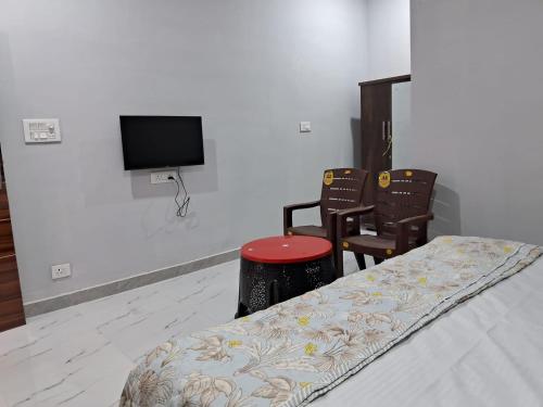 a room with a bed and two chairs and a flat screen tv at AAAC Rooms in Sundarnagar