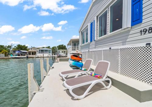 a row of lounge chairs on a dock next to the water at Oceanview Retreat with 60ft Seawall in Cudjoe Key