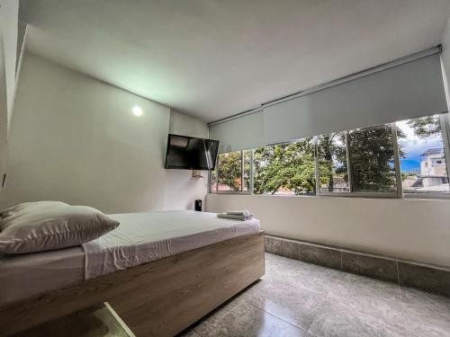 a bedroom with a bed and a large window at Neón Apartaestudios Autónomos - Recepción Digital 24H in Ibagué