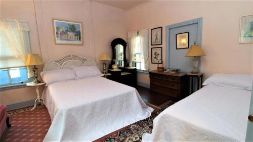 a bedroom with two beds and a dresser and windows at May Caper - Second Floor in Cape May