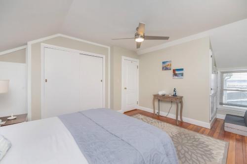 a white bedroom with a bed and a ceiling fan at Waterfront Sodus Gem, Dock Game Loft Bay View in Sodus Point