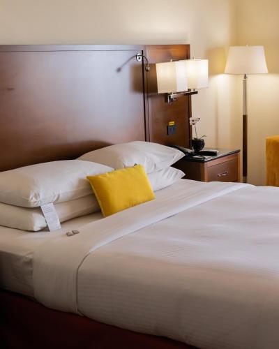 a large white bed with a yellow pillow on it at Marriott Venezuela Hotel Playa Grande in Playa Grande