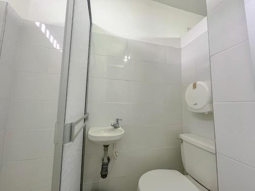a white bathroom with a toilet and a sink at Neón Apartaestudios Autónomos - Recepción Digital 24H in Ibagué