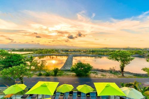 a group of green umbrellas sitting next to a river at Happy Life Memories Hoi An Hotel & Spa in Hoi An