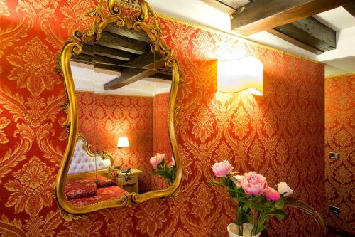 a large mirror in a room with red wallpaper at Ca' Della Loggia in Venice