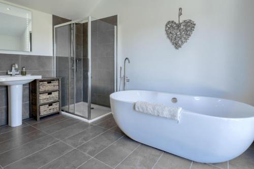 eine weiße Badewanne im Bad mit Waschbecken in der Unterkunft Oak Cottage and Hot Tub, Loch Tay in Lawers