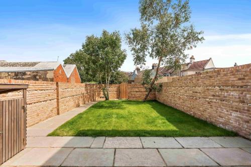 a backyard with a brick wall and a yard withgrass at Sanctuary House with Parking By My Getaways in Shoreham-by-Sea