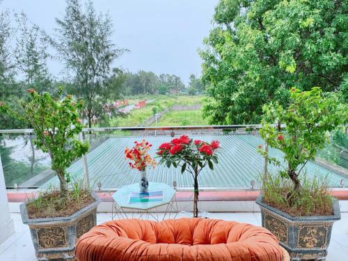 an orange couch and a table on a balcony with trees at Villa Ngân Hà in Kon Rung (1)