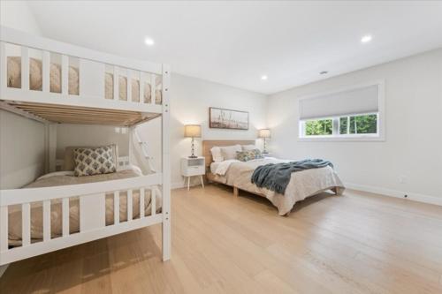 a white bedroom with two bunk beds in it at Modern Paradise In The Forest - Bruce Peninsula in Stokes Bay