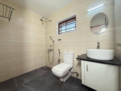 a bathroom with a toilet and a sink and a mirror at Bliss stays in Cochin