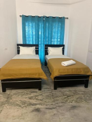 two beds in a room with blue curtains at Bliss stays in Cochin