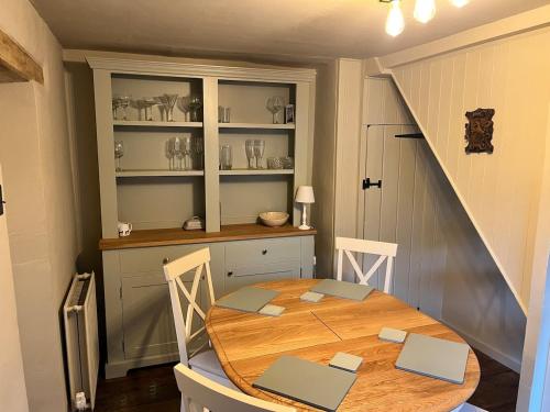 a dining room with a table and a staircase at Charming countryside cottage in Bekesbourne