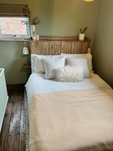 a bedroom with a large bed with white sheets and pillows at Charming countryside cottage in Bekesbourne