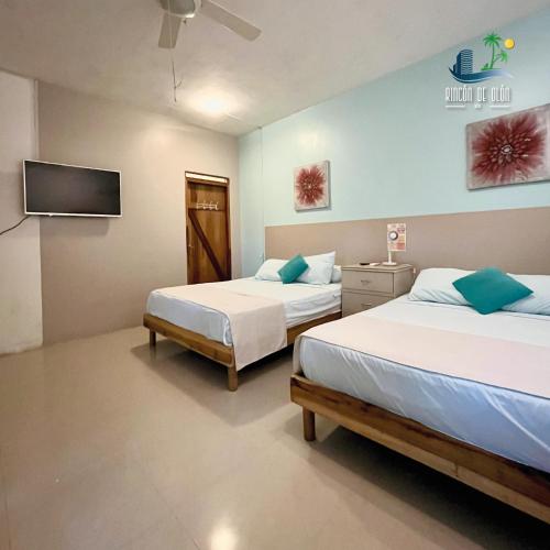 Un dormitorio con dos camas y un televisor en la pared. en Rincón d'Olón Boutique Hotel, en Olón