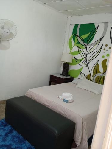 a bedroom with a bed with a black ottoman and a plant mural at Napoli Centro in Santa Ana