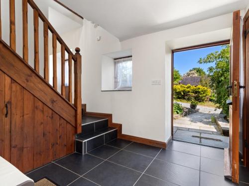 a hallway with a wooden staircase and a sliding glass door at Ysgubor Uchaf in Whitland