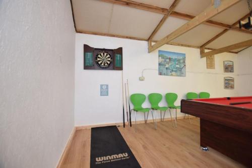 a room with a ping pong table and green chairs at The Mountains House in Blaenau-Ffestiniog