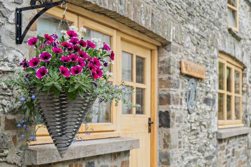 a basket of pink flowers hanging from a window at The Old Cart House - Crugybar in Rhandirmwyn