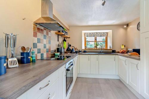 a kitchen with white cabinets and a counter top at The Old Cart House - Crugybar in Rhandirmwyn